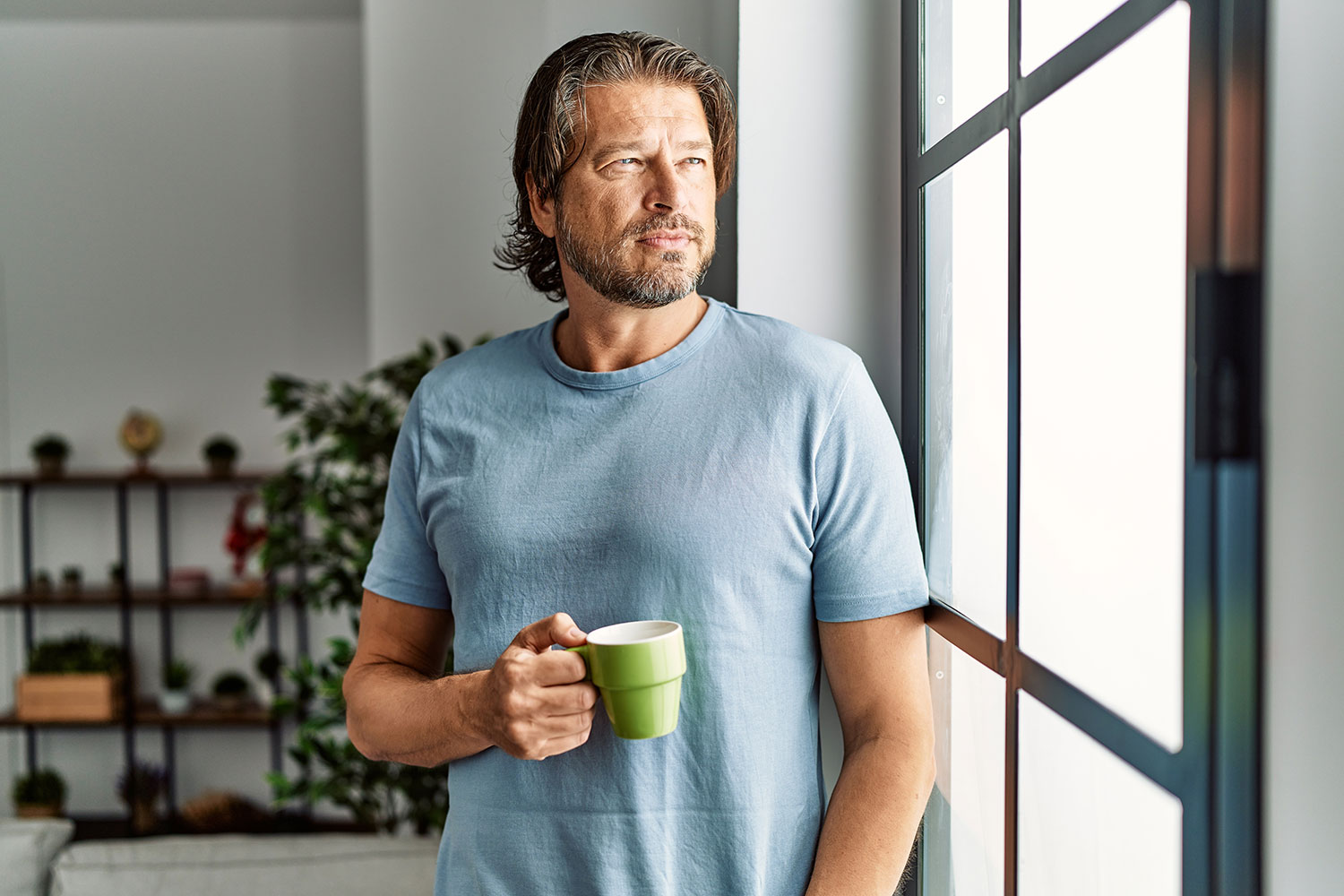 man drinking coffee looking out the window