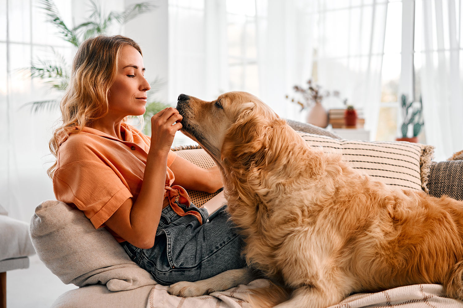 woman with golden retriever on couch