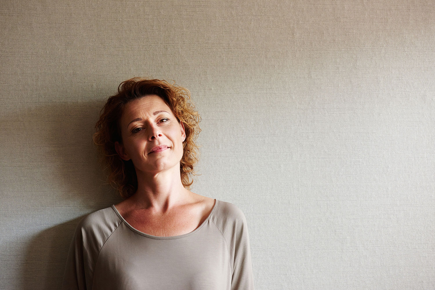 smiling woman leaning against wall